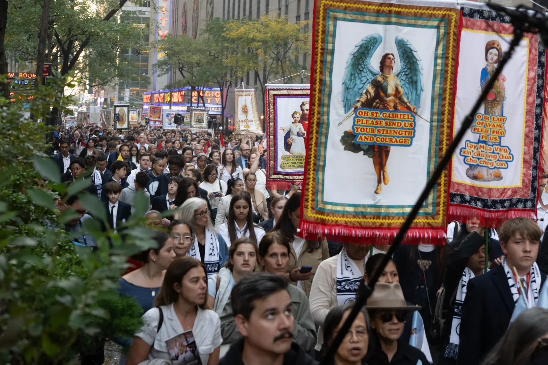Banners of the saints rise above a crowd stretching down the block. Young and old move forward together, companions on the way to Christ. | Credit: Jeffrey Bruno